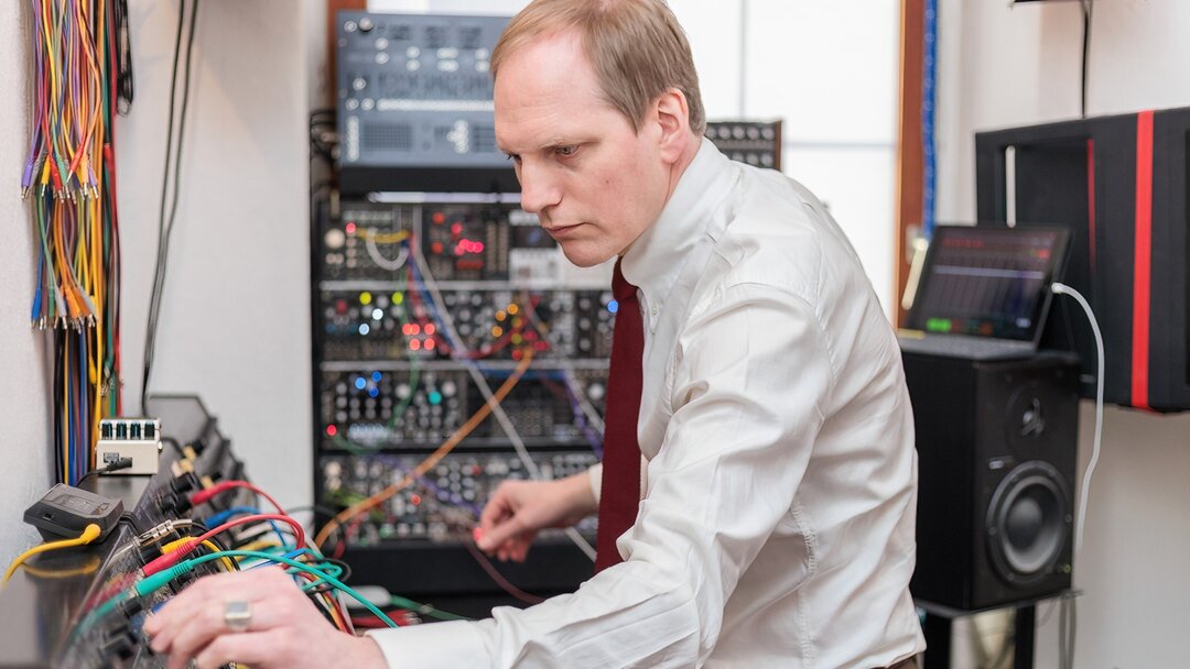 Max Knoth adjusts knobs on an analog synth in his studio